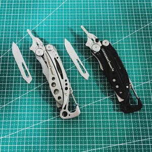 Könnte beinhalten: Zwei Multitools, eines silberfarben und eines schwarzen, mit Klingen und anderen Werkzeugen sichtbar. Das silberne Werkzeug ist mit "LEATHERMAN Skeletool" beschriftet. Die Werkzeuge liegen auf einer grünen Schneidematte.