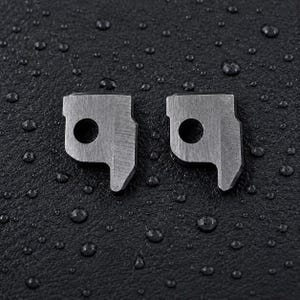 Op de afbeelding: Twee identieke metalen onderdelen met een geborstelde afwerking, elk voorzien van een rond gat en een uitgesproken hoekige vorm met een naar beneden wijzend lipje. De stukken liggen naast elkaar op een donker, getextureerd oppervlak met waterdruppels.