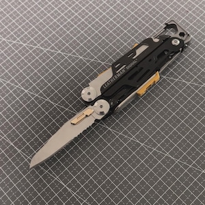 May include: A multi-tool with a partially serrated blade, featuring black and silver metal components with yellow accents. The text "LEATHERMAN SIGNAL" is visible on the tool. The tool is designed for outdoor use and survival.