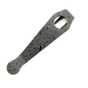 May include: A pocket clip made of Damascus steel featuring a distinct gray and black swirling pattern. The clip has a tapered shape with a rounded end and a circular cutout near the top, showcasing the intricate layered metal construction.