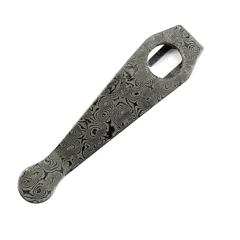 May include: A pocket clip made of Damascus steel featuring a distinct gray and black swirling pattern. The clip has a tapered shape with a rounded end and a circular cutout near the top, showcasing the intricate layered metal construction.