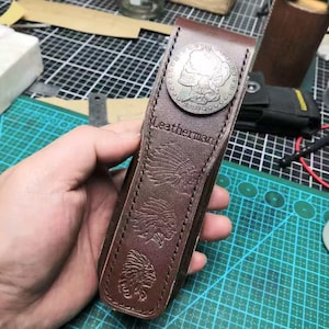 Puede incluir: Una funda Leatherman de cuero marr&oacute;n con un acento de moneda plateada. La funda presenta dise&ntilde;os en relieve de estilo nativo americano y el nombre de la marca. La funda est&aacute; dise&ntilde;ada para guardar una multiherramienta.