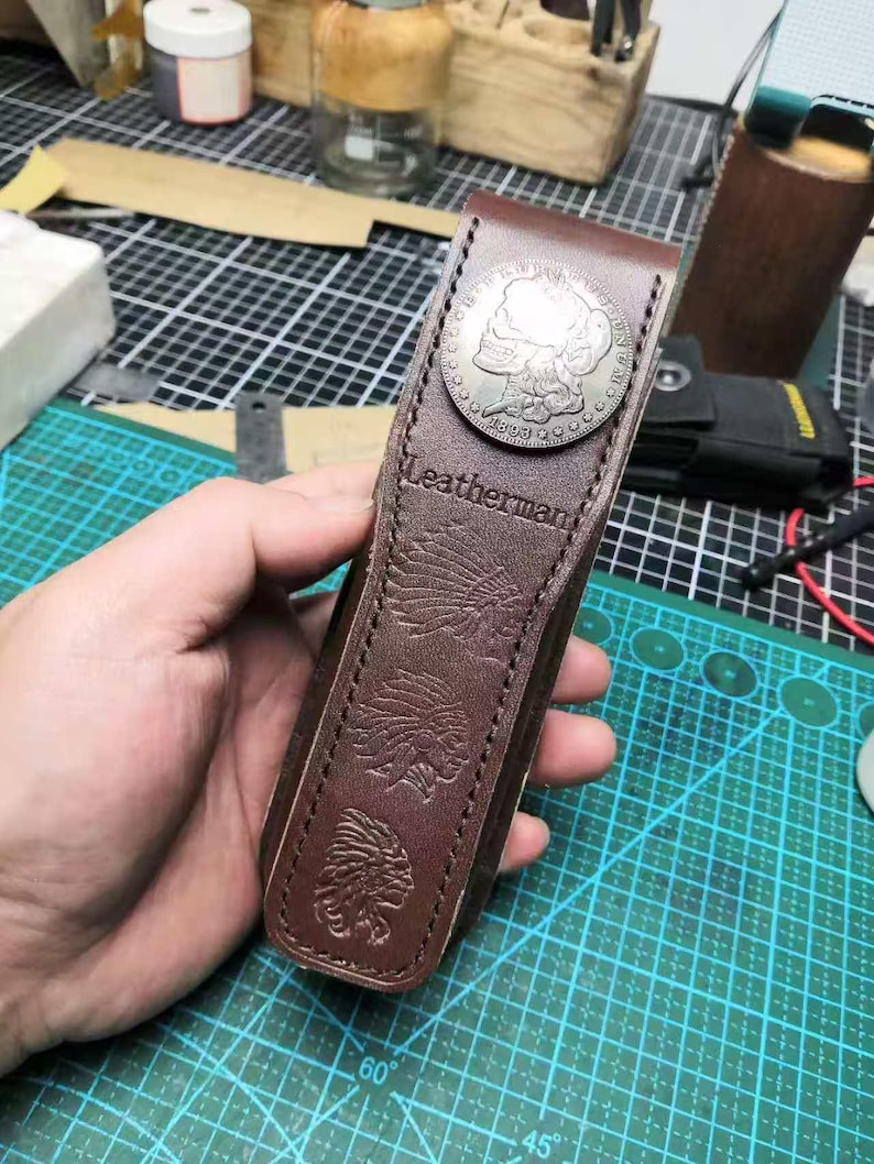 Puede incluir: Una funda Leatherman de cuero marr&oacute;n con un acento de moneda plateada. La funda presenta dise&ntilde;os en relieve de estilo nativo americano y el nombre de la marca. La funda est&aacute; dise&ntilde;ada para guardar una multiherramienta.