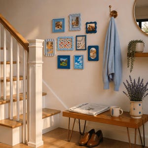 Peut inclure: Une collection de petits cadres bleus avec diverses images sur un mur beige. Un pull bleu clair est suspendu &agrave; un crochet en laiton. Un banc en bois contient un journal, une tasse et un vase de lavande. Des chaussures en cuir marron sont en dessous.