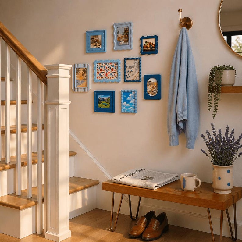 Peut inclure: Une collection de petits cadres bleus avec diverses images sur un mur beige. Un pull bleu clair est suspendu &agrave; un crochet en laiton. Un banc en bois contient un journal, une tasse et un vase de lavande. Des chaussures en cuir marron sont en dessous.