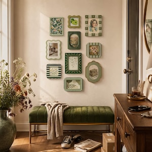 May include: A collection of framed art pieces in various shapes and sizes, arranged on a wall. The frames are in shades of green and white, with botanical and portrait imagery. A green velvet bench with gold legs sits below the artwork.