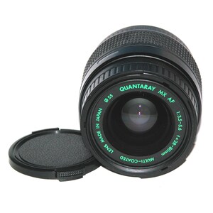 May include: A black Quantaray MX AF camera lens with a lens cap. The lens is marked with text including "LENS MADE IN JAPAN", "MULTI-COATED", "QUANTARAY MX AF", "1:3.5-5.6 f=28-80mm", and "Ø55".