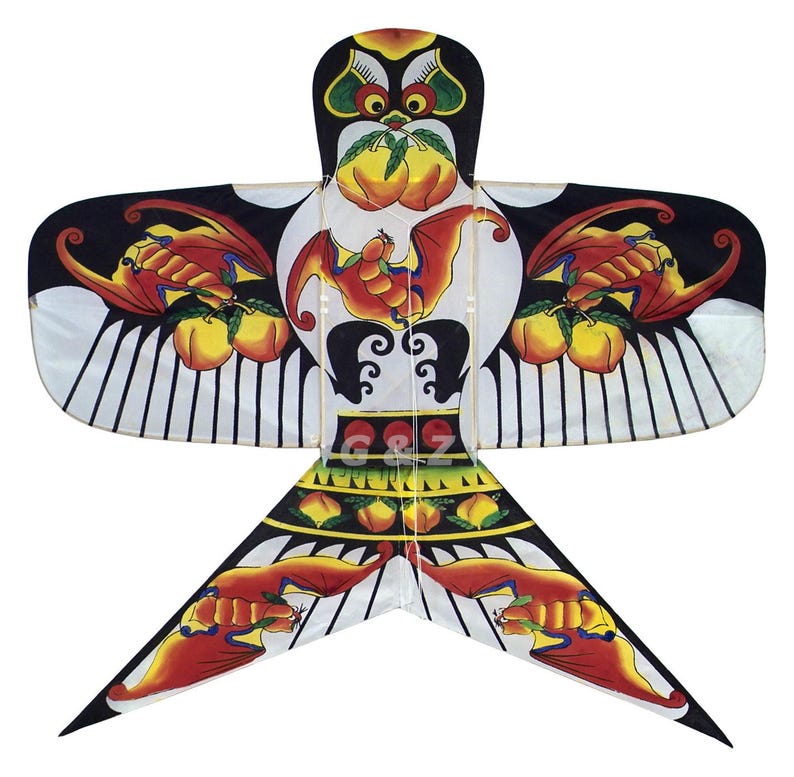 May include: A colorful kite with a central design featuring a bat and peaches, set against a white and black background. The kite has a bird-like shape with wings and a tail, and the text "G & Z" is visible.