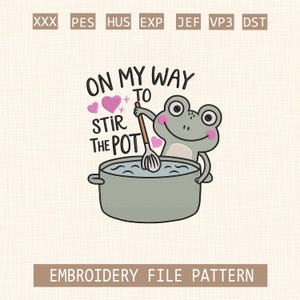 Op de afbeelding: Een borduurpatroon met een cartoonkikker die in een pot roert. De grijze kikker heeft roze wangen en houdt een houten lepel vast. De tekst "ON MY WAY TO STIR THE POT" staat boven de pot, met roze hartjes.