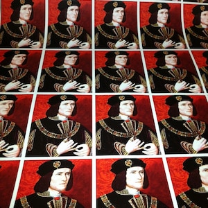 May include: A repeating pattern of a man in a black velvet robe with a gold collar and a white ruff. He is holding his hands together in front of him. The background is red.