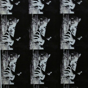 May include: A black and white photo of a person with a blurred background. The person is wearing a suit and tie and has a serious expression on their face.