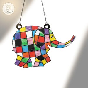 Puede incluir: Un atrapasoles de elefante de vidriera de colores con un diseño de patchwork. El elefante está compuesto por cuadrados de varios colores, incluyendo rojo, amarillo, azul y negro. Cuelga de una cadena y presenta un ojo circular y una trompa curvada.