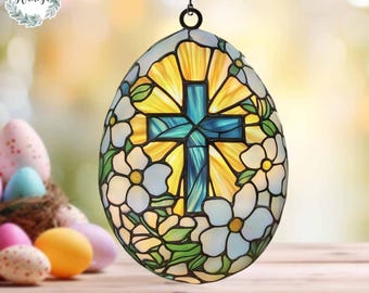 May include: An egg-shaped stained glass hanging lamp featuring a teal cross against a yellow and white background. The lamp is surrounded by white flowers and green leaves. A chain suspends the lamp. Easter theme.