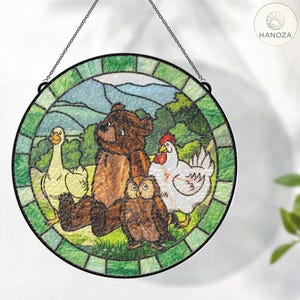 May include: Round stained glass panel featuring a bear, owl, duck, and chicken in a pastoral scene. The artwork is framed by a green border and hangs from a chain. The design has a whimsical, storybook feel.