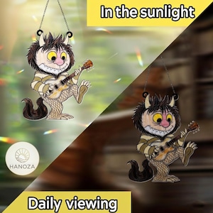 Op de afbeelding: Een grillige zonnevanger met een stripfiguur die gitaar speelt. Het personage heeft een bruine manen, grote gele ogen en een gestreept shirt. De tekst "In the sunlight" en "Daily viewing" worden weergegeven.
