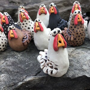 May include: A collection of ceramic chickens in various colors and patterns, including black, white, brown, and polka dots. The chickens have exaggerated features, such as large eyes and beaks.