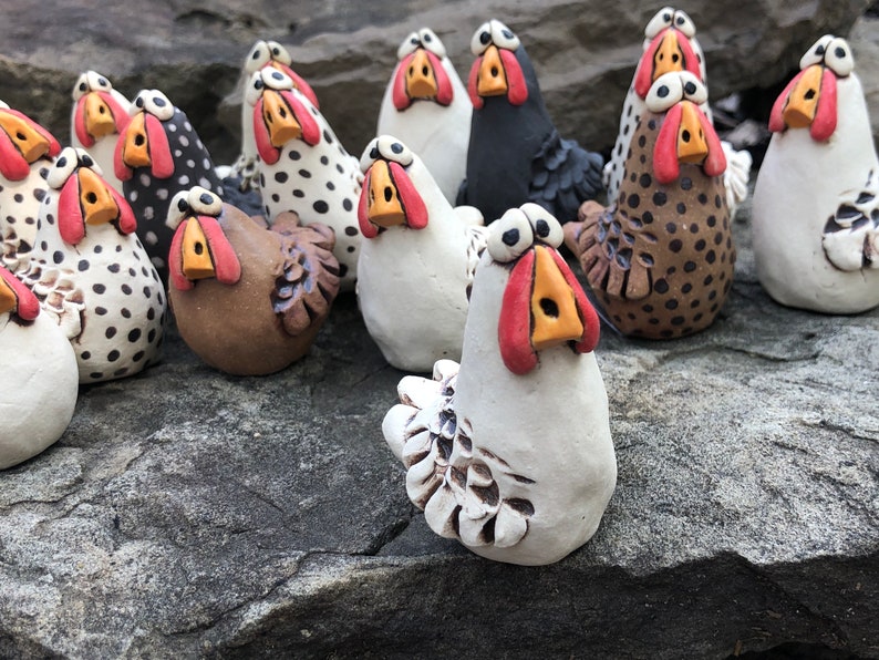 May include: A collection of ceramic chickens in various colors and patterns, including black, white, brown, and polka dots. The chickens have exaggerated features, such as large eyes and beaks.