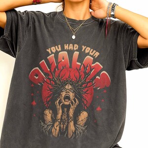 May include: A charcoal gray short-sleeve t-shirt featuring a graphic print of a screaming figure with a crown of thorns and branches. The text "YOU HAD YOUR CHANCE" is printed in a distressed red and beige font above the central illustration.