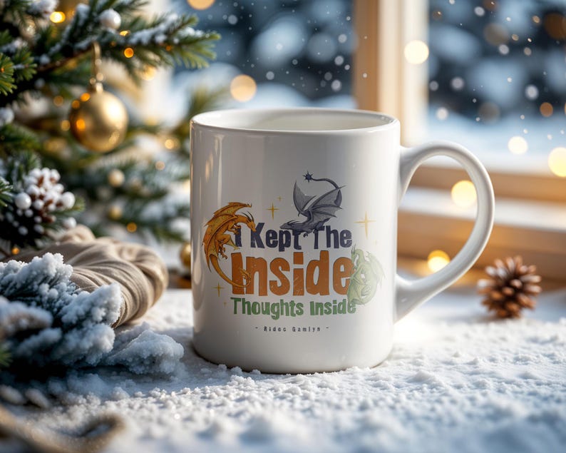 May include: White ceramic mug with the text "I Kept The Inside Thoughts Inside" and dragon illustrations in orange, gray, and green. The mug has a curved handle and is set against a snowy background with a Christmas tree.