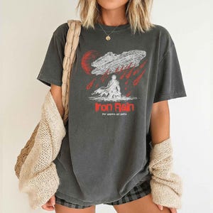 Op de afbeelding: Donkergrijs t-shirt met een grafisch ontwerp. Het ontwerp bevat de tekst "Iron Rain" in het rood, een ruimteschip en een figuur. De zin "Per Aspera Ad Astra" staat eronder.