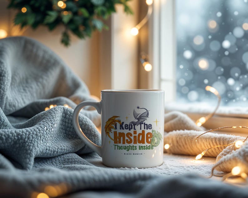 May include: White ceramic mug with the text "I Kept The Inside Thoughts Inside" and a dragon graphic. The mug has a curved handle and is set against a cozy, winter-themed background with soft lighting and a blanket.