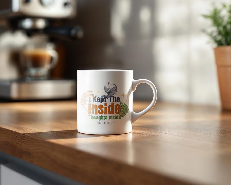 May include: White ceramic mug with the text "I Kept The Inside Thoughts Inside" in a stylized font. The mug features a dragon graphic and other decorative elements. The mug is on a wooden surface.