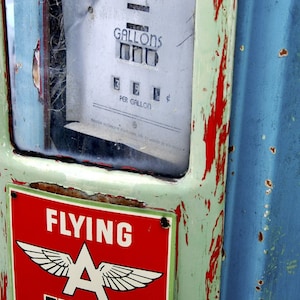 Puede incluir: Una bomba de gasolina vintage con un esquema de color rojo, blanco y azul. La bomba tiene un letrero que dice "Flying A Ethyl Gasoline". La bomba tiene un indicador de precio que dice "This Sale $____" y "Gallons ____".