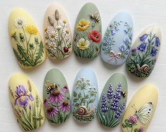 May include: A collection of ten artificial nails, each adorned with detailed, three-dimensional floral and insect designs. The nails feature various colors, including yellow, green, blue, and purple, with depictions of dandelions, daisies, bees, and butterflies.