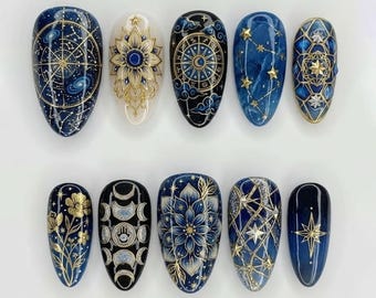 May include: Ten almond-shaped nail designs with celestial and floral patterns. The nails are painted in navy blue, gold, and white, featuring constellations, flowers, and geometric shapes. The designs create a mystical aesthetic.