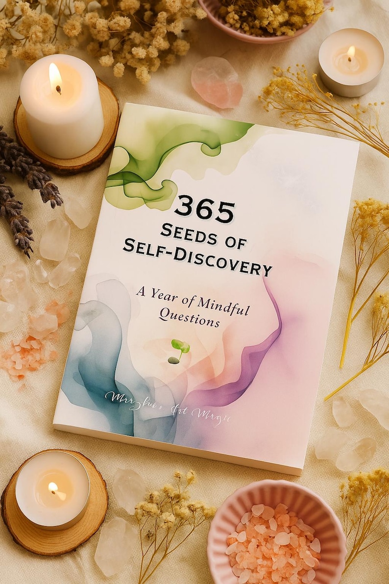 May include: A book titled "365 Seeds of Self-Discovery" with a watercolor design. The cover features green, blue, and purple hues. The book is surrounded by candles, crystals, and dried flowers, creating a serene aesthetic.