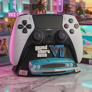 Op de afbeelding: Een zwart-witte gamecontroller op een aangepaste standaard met het Grand Theft Auto VI-logo en een miniatuur voorbumper van een lichtblauwe oldtimer. De standaard bevat aan beide kanten kleine kentekenplaten met de tekst GTA VI.