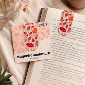 Op de afbeelding: Een magnetische bladwijzer met een herfstpatroon met pompoenen, paddenstoelen en bladeren in tinten oranje, rood en bruin. De bladwijzer is rechthoekig met afgeronde hoeken en de tekst "Magnetic Bookmark Fall pattern".