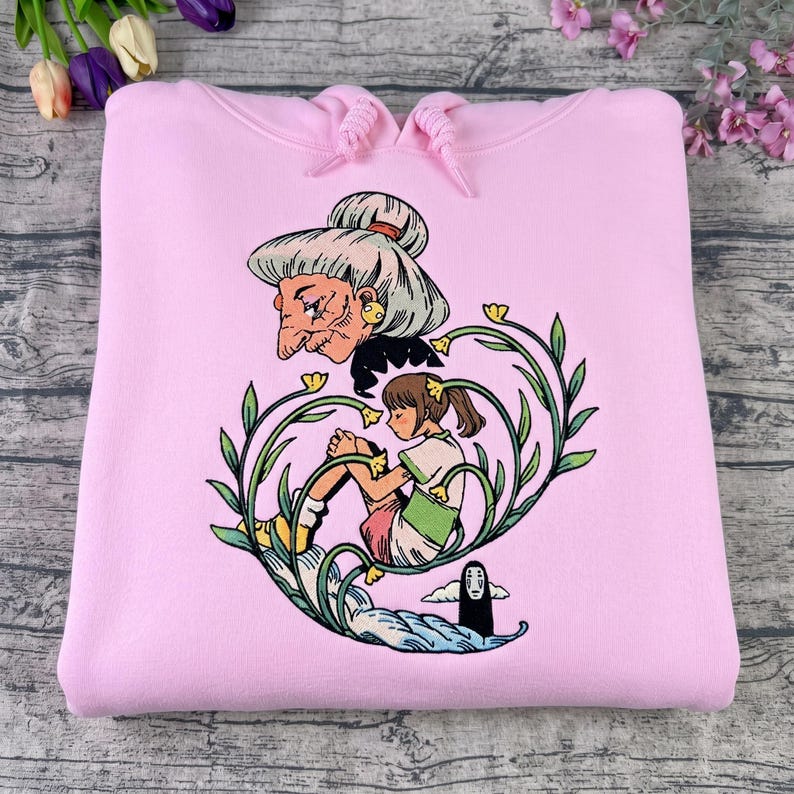 Puede incluir: Sudadera con capucha rosa claro con un dise&ntilde;o gr&aacute;fico colorido de la pel&iacute;cula de animaci&oacute;n El Viaje de Chihiro. El dise&ntilde;o incluye a Yubaba, Chihiro y Sin Cara, rodeados de elementos florales. La sudadera tiene una capucha con cord&oacute;n.