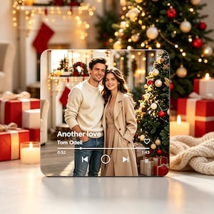 May include: A square acrylic plaque featuring a photograph of a couple standing in front of a Christmas tree. The image includes a music player interface overlay with the text Another love, Tom Odell, and playback controls with a progress bar.