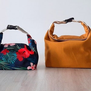 May include: Two lunch bags, one with a tropical floral print and the other a solid mustard yellow.