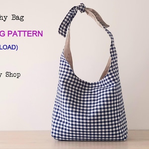 Może przedstawiać: Niebiesko-biała torba typu slouchy w kratę z brązowym paskiem. Torba stoi na drewnianej powierzchni. Tekst na zdjęciu brzmi "The Daily Slouchy Bag DIGITAL PDF SEWING PATTERN (INSTANT DOWNLOAD) by Story Quilt Etsy Shop."