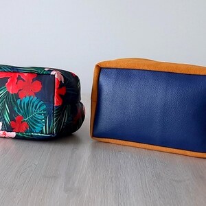 May include: Two rectangular fabric bags. One bag is blue with a tropical floral print. The other bag is blue with a solid orange border.