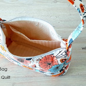 May include: A white fabric bag with a floral print in shades of orange, blue, and white. The bag has a single strap and a zipper closure. The bag is open and the inside is lined with a beige fabric. The bag has an inner pocket. The text "The Urban Baguette Bag Sewing Pattern by Story Quilt" is visible at the bottom of the image.