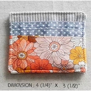 May include: A small gray fabric wallet with a floral print and a blue polka dot fabric lining. The wallet measures 4 inches by 3 inches. DIMENSION: 4 (1/4)" X 3 (1/2)"
