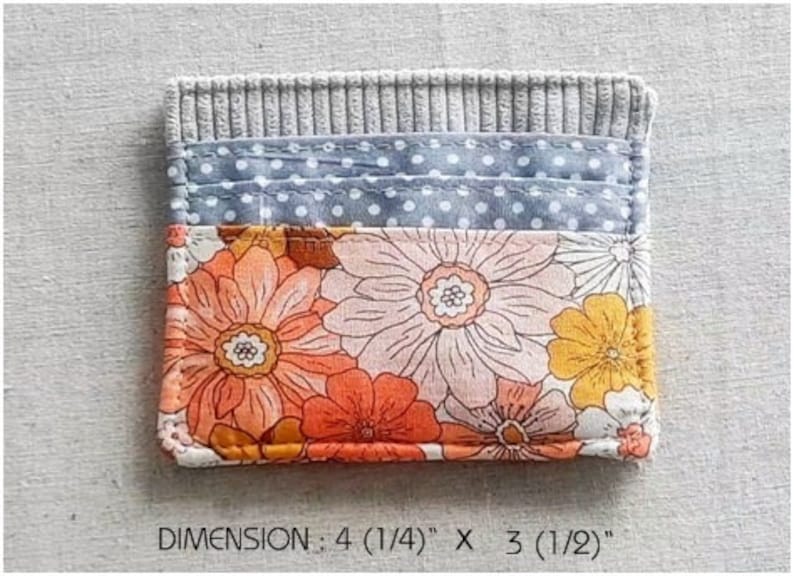 May include: A small gray fabric wallet with a floral print and a blue polka dot fabric lining. The wallet measures 4 inches by 3 inches. DIMENSION: 4 (1/4)" X 3 (1/2)"