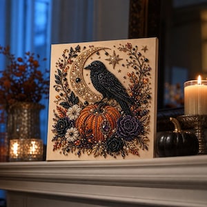 May include: A square wall art piece featuring a diamond painting design of a black raven perched on an orange pumpkin. The scene includes a gold crescent moon, a star, and floral accents in black, white, and orange beads on a light tan background.
