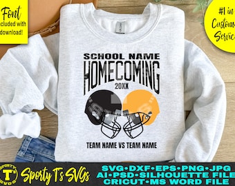 May include: A gray sweatshirt with a black and white graphic design that says "SCHOOL NAME HOMECOMING 20XX" with two football helmets facing each other. The helmets are black and gold. The text "TEAM NAME VS TEAM NAME" is below the helmets.