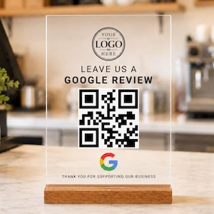 May include: A clear rectangular acrylic sign with a wooden base featuring a circular logo placeholder, the text LEAVE US A GOOGLE REVIEW, a black and white QR code, a colourful Google G icon, and the text THANK YOU FOR SUPPORTING OUR BUSINESS.