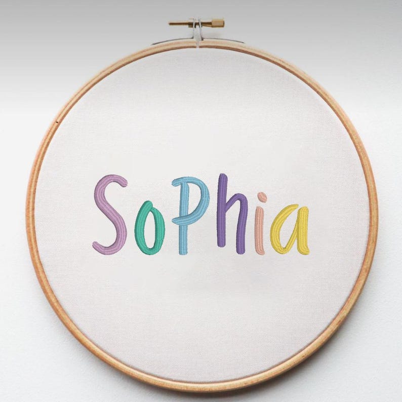 May include: An embroidery hoop with the name "Sophia" stitched in colorful thread. The letters are in a playful, handwritten style, with each letter a different pastel color: purple, teal, blue, purple, yellow, and pink.