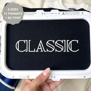 May include: A white rectangular embroidery hoop containing black fabric with the word CLASSIC embroidered in white thread. A gray overlay displays the text 6 SIZES, 11 FORMATS + BX FONT. The hoop frame includes safety warnings and the text 8x13 Mighty Hoop.
