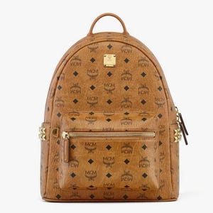 Può includere: Uno zaino marrone con un motivo ripetuto di loghi neri "MCM". Lo zaino ha una maniglia superiore, una tasca frontale con cerniera e hardware color oro. La borsa ha una forma rettangolare ed è realizzata in materiale simile alla pelle.