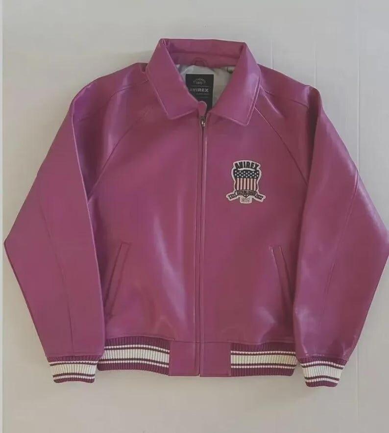 May include: A magenta leather jacket with a zip-up front, collared neckline, and ribbed cuffs and hem with white stripes. An emblem is on the chest. The jacket has two front pockets.