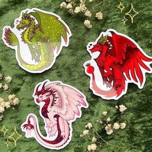 May include: Three fantasy dragon stickers. One is green with yellow accents, another is red, and the third is pink and burgundy. Each sticker has a unique design and pose, with a heart symbol above each dragon.