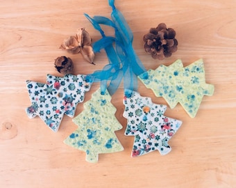 May include: Five ceramic Christmas tree ornaments with blue and green snowflake patterns. The ornaments are hanging from blue ribbon.