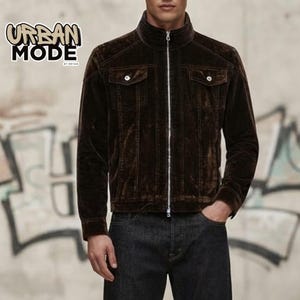 Puede incluir: Una chaqueta de pana marrón oscuro con cuello alto, cremallera plateada de cuerpo entero y dos bolsillos en el pecho con cierre de botón. El texto "URBAN MODE BY BRYAN" es visible en la esquina superior izquierda de la imagen.